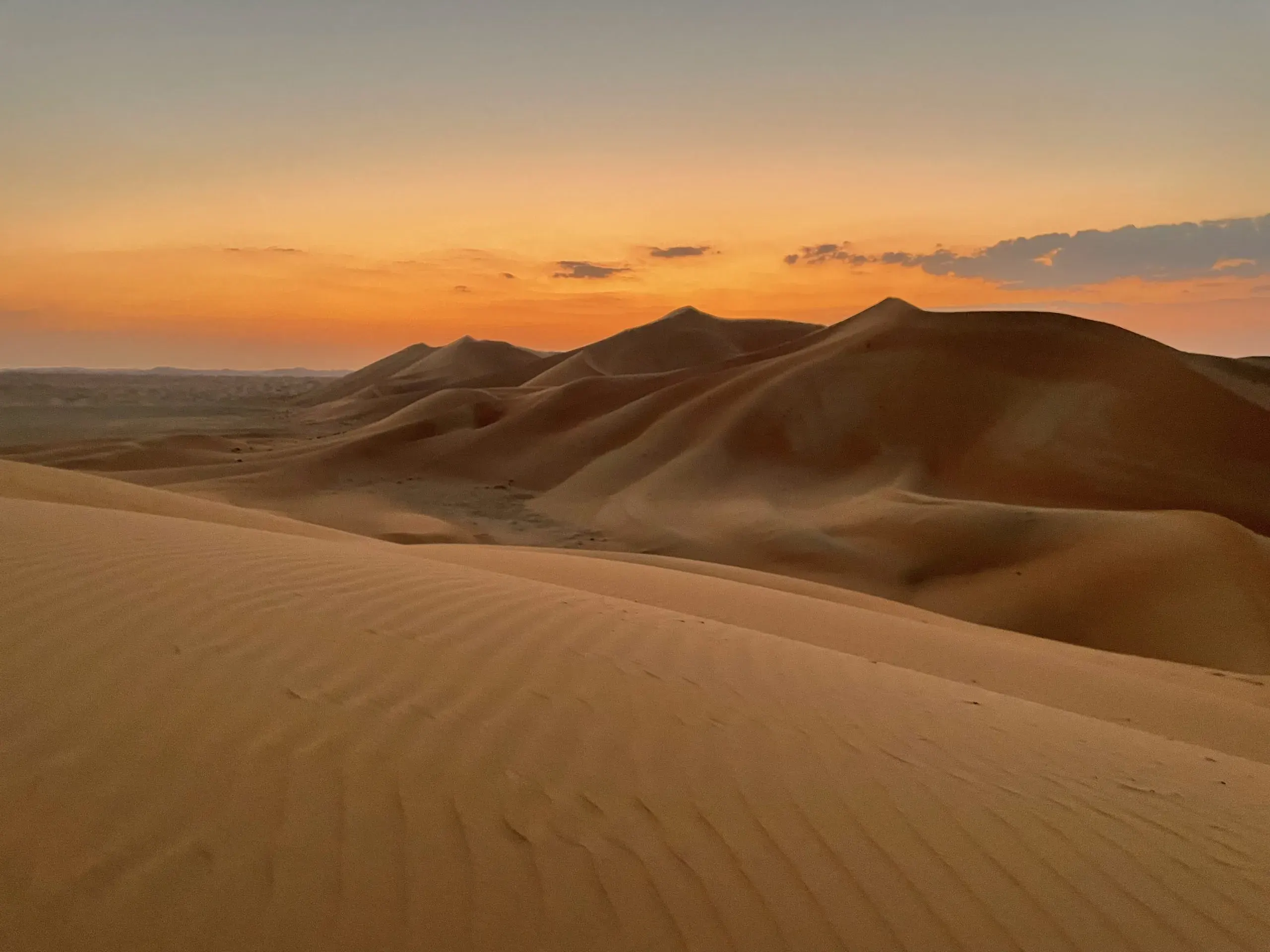 The sun setting behind a range of dunes in the Empty Quarter